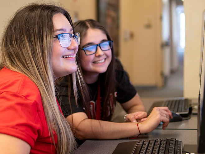 Two students smiling at a computer screen